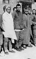 North Korean prisoners of war stand outside of an incarceration center.