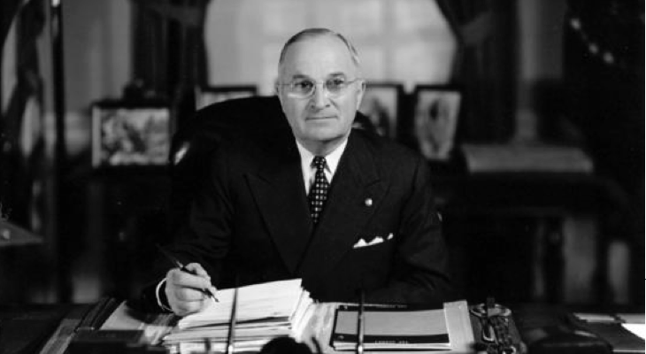 President Truman signing documents on desk